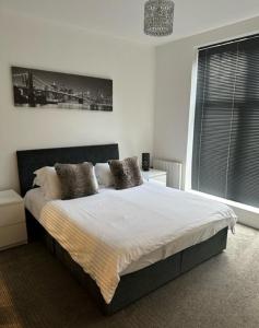 1 dormitorio con 1 cama con sábanas y almohadas blancas en Stunning Flat with Parking Free near Sutton Station en Cheam