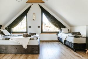 2 Betten in einem Schlafzimmer im Dachgeschoss mit Fenstern in der Unterkunft Domki Bliżej Natury Rabka-Zdrój in Rabka-Zdrój