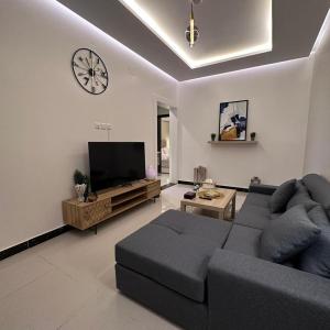un soggiorno con divano e orologio sul muro di رغيد للشقق الفندقية حائل a Hail