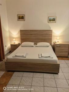 a bedroom with a large bed with white sheets and two tables at Lovely Bosnian Home in Mostar