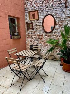 une table et des chaises installées à côté d'un mur de briques dans l'établissement N3 Le Colvert - La Maison Sévigné Appart Hôtel, à Béthune