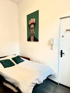 - une chambre avec un lit orné d'une peinture de femme dans l'établissement N3 Le Colvert - La Maison Sévigné Appart Hôtel, à Béthune