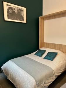 - un lit avec 2 oreillers bleus dans une chambre dans l'établissement N3 Le Colvert - La Maison Sévigné Appart Hôtel, à Béthune