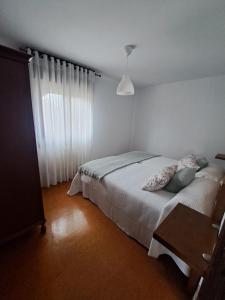 a bedroom with a bed and a table and a window at A Reitoral in Vigo
