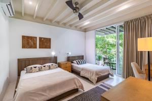 a bedroom with two beds and a table and a desk at Casa Pochote in Santa Teresa Beach