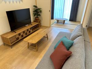 sala de estar con sofá y TV de pantalla plana en Bears Stay Kumejima Villa - Vacation STAY 01033v, en Kumejima