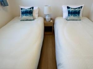 2 Betten nebeneinander in einem Zimmer in der Unterkunft Bears Stay Kumejima Villa - Vacation STAY 00998v in Kumejima