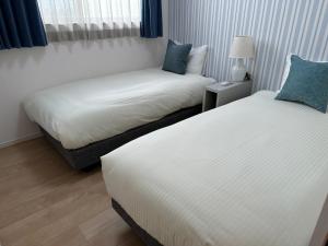 sypialnia z 2 łóżkami i lampką w obiekcie Bears Stay Kumejima Villa - Vacation STAY 01040v w Kumejimie
