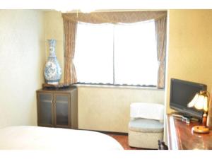 1 dormitorio con 1 cama, TV y ventana en Green Hotel Rich Tokugawaen - Vacation STAY 02720v, en Okazaki