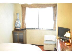 a bedroom with a bed and a tv and a window at Green Hotel Rich Tokugawaen - Vacation STAY 02720v in Okazaki