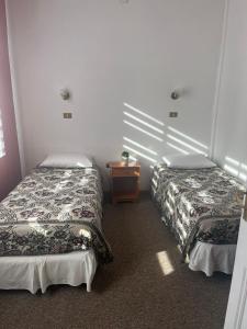 Habitación con 2 camas y mesita de noche. en HOSTAL AYELEN en Punta Arenas