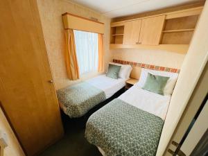 a small room with two beds and a window at 2 Bedroom Caravan SHS3, Sandhills, Bembridge in Bembridge