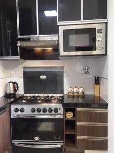 a kitchen with a stove and a microwave at Lujoso Apartamento de 1 dormitorio, cerca de Equipetrol, moderno 100% amoblado con Netflix, Parqueo gratuito y WIFI de 100MB. in Santa Cruz de la Sierra