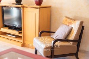 uma sala de estar com uma cadeira e uma televisão em El Nautico Relax in Golf del Sur em San Miguel de Abona