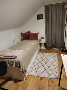 1 dormitorio con cama con almohadas rojas y alfombra en Sahlin - Kattarp, en Kattarp