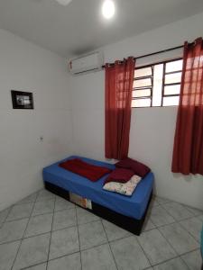 - une chambre avec un lit bleu dans une pièce dotée de rideaux rouges dans l'établissement Seu Apto na Praia da Costa 7 Completo 2Q 2B 2S Ar Cond Geladeira Fogao TV Maq Lavar Centro Sem escadas, à Vila Velha