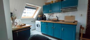 a kitchen with blue cabinets and a washing machine at Strand zuid in Egmond aan Zee