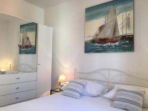 sypialnia z białym łóżkiem i obrazem łodzi żaglowej w obiekcie Apartments Eastern Paradise w Bol