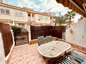 een patio met een tafel en stoelen en een hek bij Gran Alacant Bea's house in Gran Alacant
