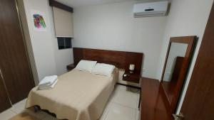 Dormitorio pequeño con cama y espejo en Lujoso Apartamento de 1 dormitorio, cerca de Equipetrol, moderno 100% amoblado con Netflix, Parqueo gratuito y WIFI de 100MB., en Santa Cruz de la Sierra