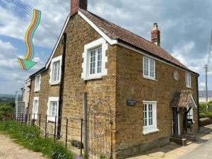 an old brick house with a rainbow on it at Strongate View Apartment - cosy stylish rural Jurassic coast & Bridport nearby in Netherbury