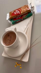 a cup of coffee on a plate with a bag of chocolate at Ap Confort Premium in Campinas