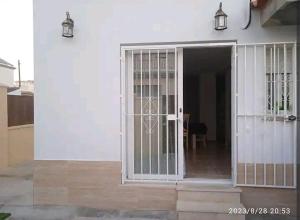 an open door of a white house with two lights at Casa en Jerez con patio cerca de la playa y de la sierra in Jerez de la Frontera