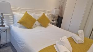 Una cama blanca con almohadas amarillas y toallas. en Luxury Cardiff Apartment with Free parking, Free high-speed internet, Fully Equipped Kitchen, en Cardiff