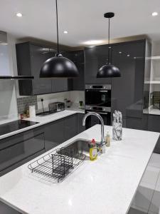 a kitchen with black cabinets and a sink and two black lights at Woodland Green - BHX, NEC, HS2 in Marston Green