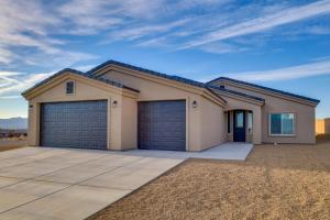 a house with two garage doors in a driveway at Modern Fort Mohave Home with Patio and Grill! in Fort Mohave