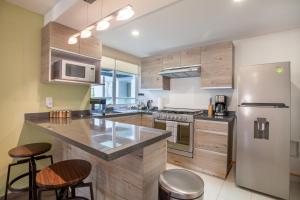 uma cozinha com armários de madeira e um frigorífico de aço inoxidável em Moderno Mexicano 3BR/2BA 200Mbps em Cidade do México