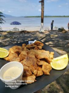 a plate of fried food with a drink and lemon slices at Pousada e Restaurante Frente ao Mar in Cananéia