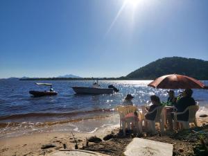 un gruppo di persone seduti a un tavolo sulla spiaggia di Pousada e Restaurante Frente ao Mar a Cananéia