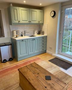 a kitchen with green cabinets and a table at Strongate View Apartment - cosy stylish rural Jurassic coast & Bridport nearby in Netherbury