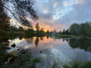 - une vue sur un lac avec le coucher du soleil en arrière-plan dans l'établissement Niebieski Domek, 