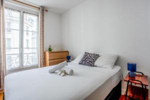 um quarto com uma grande cama branca e uma janela em Charming Parisian flat in the 11th arrondissement - Welkeys em Paris