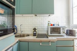 a kitchen with a microwave and a sink at Charming Parisian flat in the 11th arrondissement - Welkeys in Paris