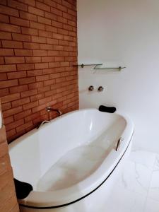 a white bath tub in a bathroom with a brick wall at Pousada Estância da Pinha in Santo Antônio do Pinhal