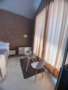 um quarto com uma cama, 2 cadeiras e uma mesa em Pousada Estância da Pinha em Santo Antônio do Pinhal