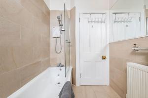 La salle de bains est pourvue d'une baignoire blanche et d'une douche. dans l'établissement Lady Road Apartment, à Édimbourg