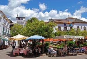 um grupo de pessoas sentadas em mesas com guarda-chuvas em Ap. Marbella centro em Marbella
