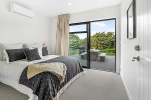 ケンブリッジにあるLakeSide Karapiro Downstairs Apartmentのベッドとガラスの引き戸のある寝室