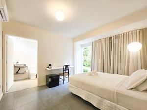 1 dormitorio con cama, escritorio y ventana en Pousada Quinta da Margem, en Florianópolis