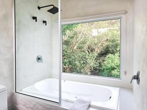 baño con bañera y ventana grande en Pousada Quinta da Margem, en Florianópolis