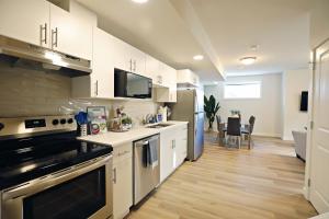 une cuisine avec des placards blancs et une salle à manger dans l'établissement Central Suite King Beds,Long Stays,Disney+, à Edmonton