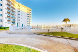 un bâtiment avec une clôture blanche à côté de la plage dans l'établissement Regency Towers W 101, à Pensacola Beach