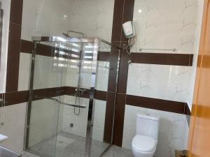 ein Bad mit einer Glasdusche und einem WC in der Unterkunft 4-bedroom City view Town House Accra in Accra