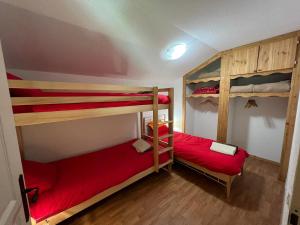 2 stapelbedden in een kamer met rode lakens bij Montagne Duplex-Orelle 9 pers. avec SPA in Orelle