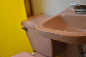 La salle de bains est pourvue d'un lavabo rose et de toilettes. dans l'établissement Hostal Quinto Sol Huamantla, à Huamantla