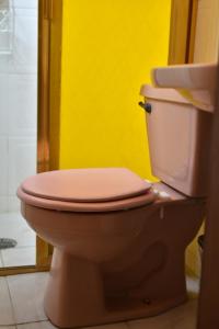 a pink toilet in a bathroom with a yellow wall at Hostal Quinto Sol Huamantla in Huamantla